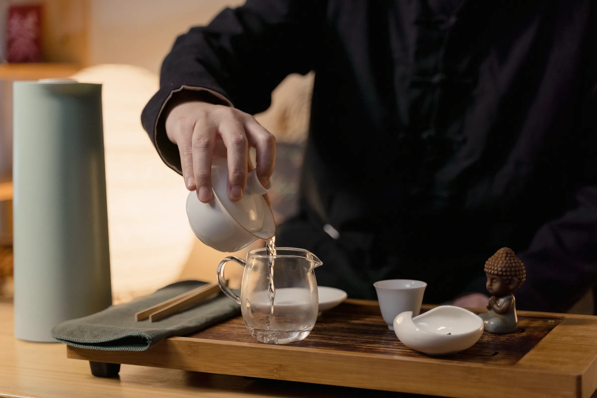 A long-spouted pot pouring into a small cup